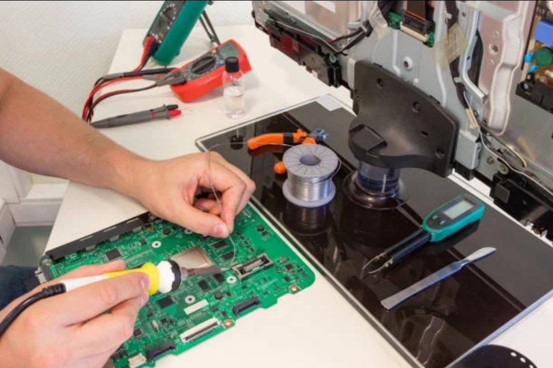 Technician soldering TV motherboard components during repair